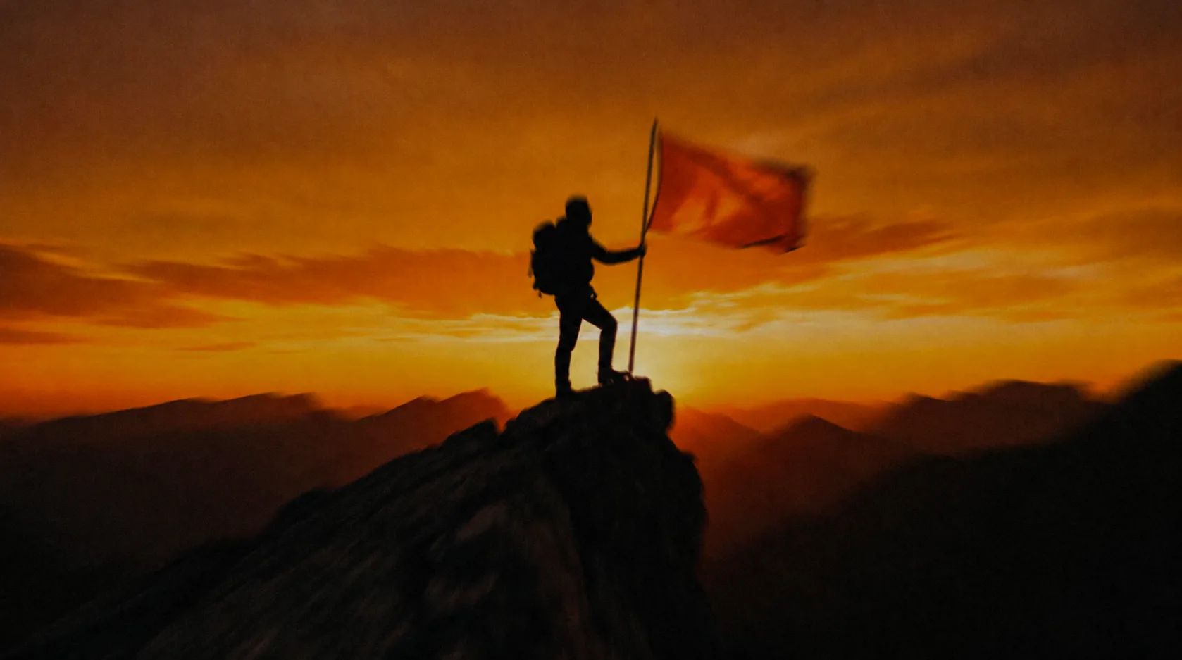 Alpinista fincando uma bandeira laranja no topo da montanha ao pôr do sol